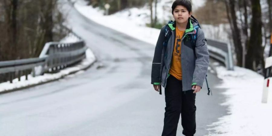 Marc läuft eine kurvige Landstrasse entlang. Der Junge muss rund zwei Kilometer zu Fuss zur Haltestelle seines Schulbusses laufen. Foto: Nicolas Armer