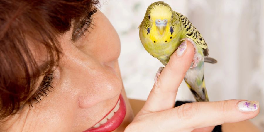 Lächelnde Frau mit Vogel auf der Hand