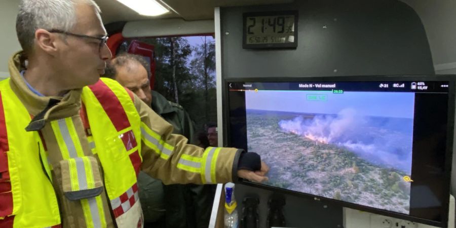 Der Feuerwehrkommandant Francis Cloth (l) zeigt den Moorbrand auf einem Bildschirm.