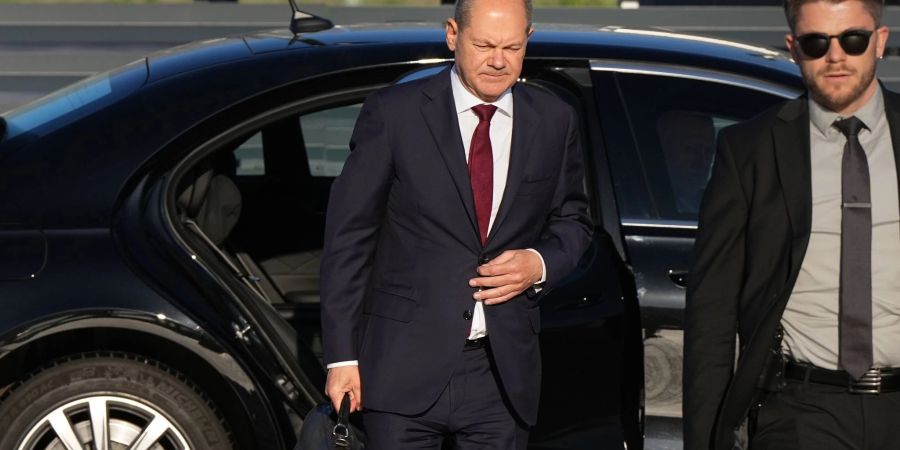 Bundeskanzler Olaf Scholz (l, SPD) kommt zum Start einer zweitägigen Reise auf dem militärischen Teil des Flughafens Berlin Brandenburg BER an und steigt aus einer Limousine.