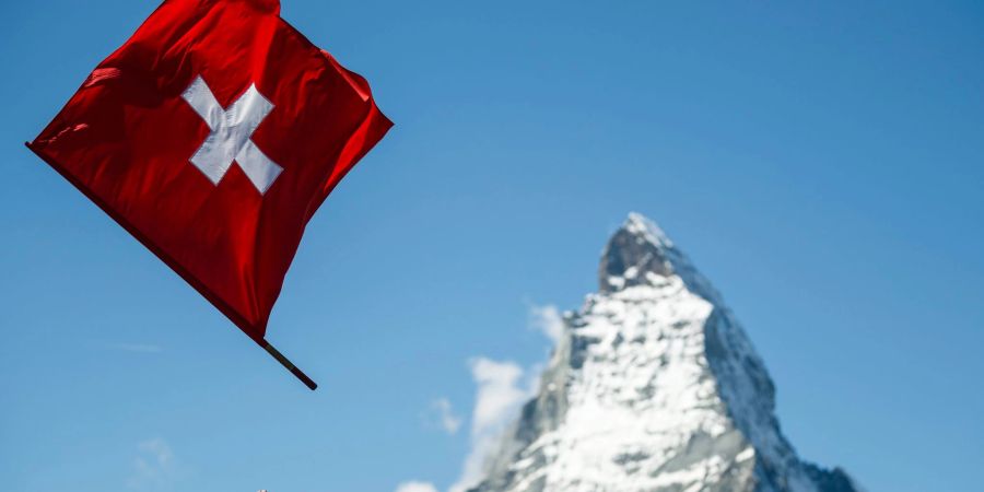 Ein Fahnenwerfer mit der Schweizer Flagge in Aktion vor der Kulisse des Matterhorns.