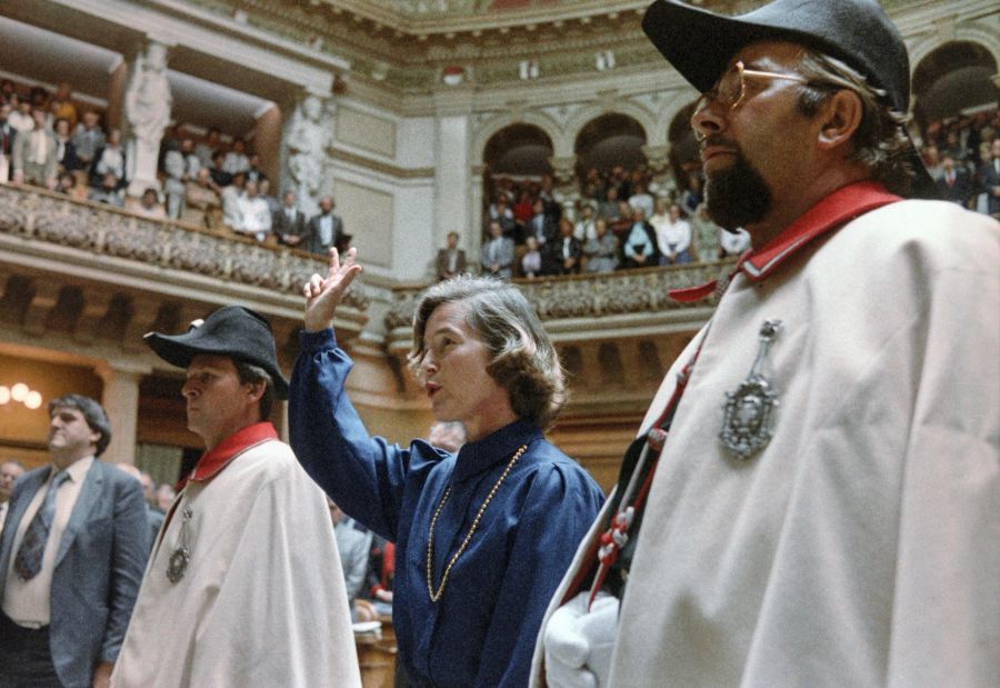 Vereidigung der ersten Frau zur Bundesrätin: In Begleitung von zwei Weibeln hebt Elisabeth Kopp am 2. Oktober 1984 in Bern bei ihrer Vereidigung im Nationalratssaal die rechte Hand zum Schwur. (KEYSTONE/Str)