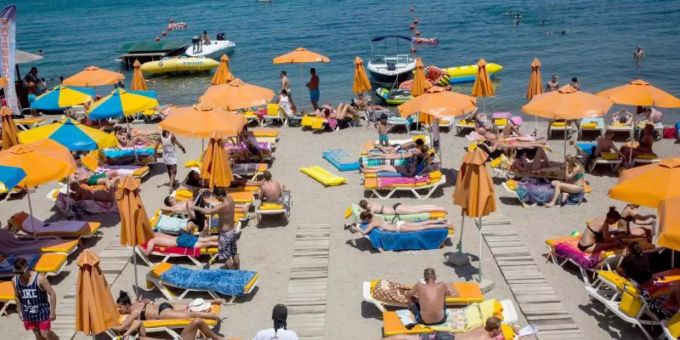 Touristen geniessen die Sonne an einem Strand auf der griechischen Insel Kos. Foto: Santi Palacios/dpa ferien ukraine krieg