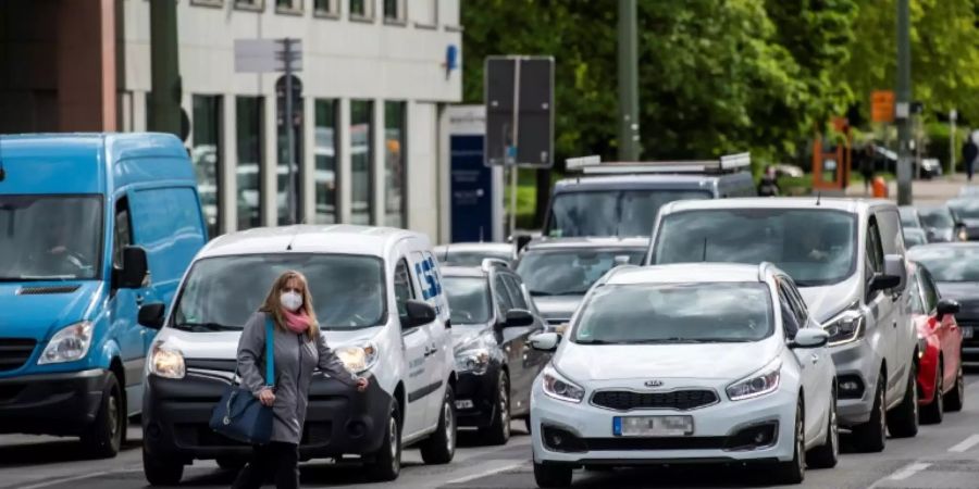 Frau mit Atemmaske vor Autoschlange in Berlin