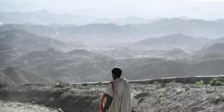 Ein Mann geht entlang einer staubigen Landstrasse in Äthiopien. 3,5 Milliarden Menschen würden in etwa 50 Jahren in Gebieten leben, in der die jährliche Durchschnittstemperatur mehr als 29 Grad Celsius beträgt - sollte der Ausstoss der Treibhausgase nicht gemindert werden. Foto: Britta Pedersen/dpa-Zentralbild/dpa