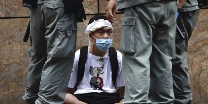 Bereitschaftspolizisten stehen im Hongkonger Central District um einen auf dem Boden sitzenden Demonstranten. Foto: Kin Cheung/AP/dpa Bereitschaftspolizisten stehen im Hongkonger Central District um einen auf dem Boden sitzenden Demonstranten. Foto: Kin Cheung/AP/dpa