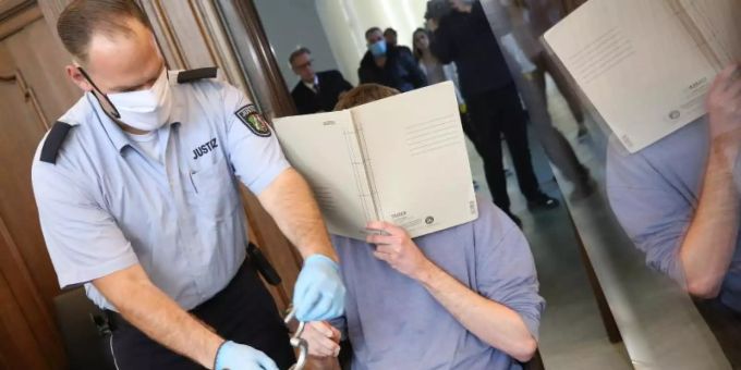 Ein Justizbeamter nimmt dem Angeklagten vor Prozessbeginn die Handschellen ab. Foto: Roland Weihrauch/dpa-Pool/dpa Ein Justizbeamter nimmt dem Angeklagten vor Prozessbeginn die Handschellen ab. Foto: Roland Weihrauch/dpa-Pool/dpa