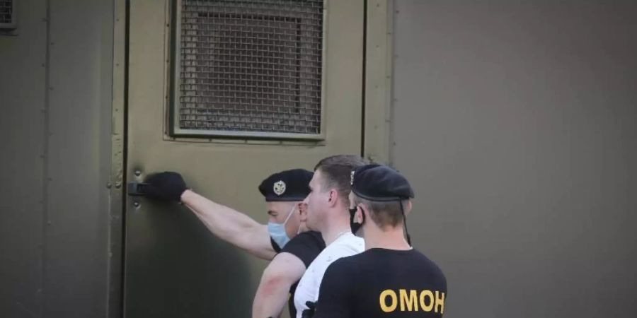 Polizeibeamte mit Mundschutzmasken halten während einer Kundgebung in Minsk einen Demonstranten fest. Foto: Str/AP/dpa