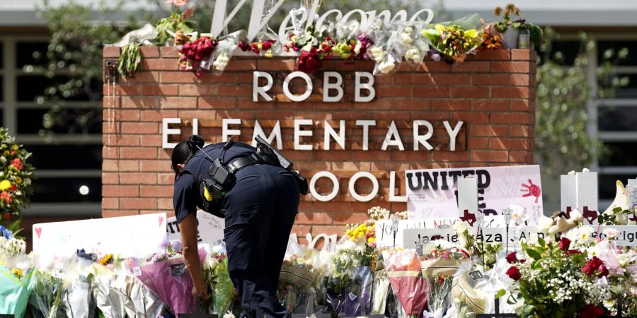 Eine Polizistin legt Blumen vor der Grundschule im texanischen Uvalde nieder.