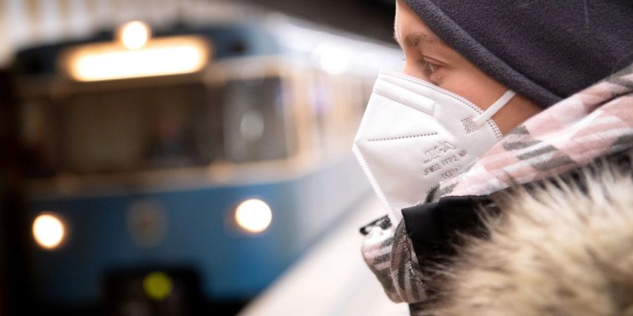 Ein Frau mit FFP2-Maske wartet auf die Bahn.