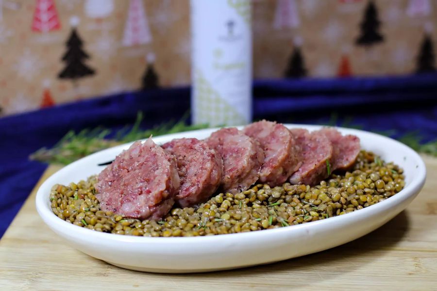 Wurst auf Linsen auf ovaler Platte auf Holztisch