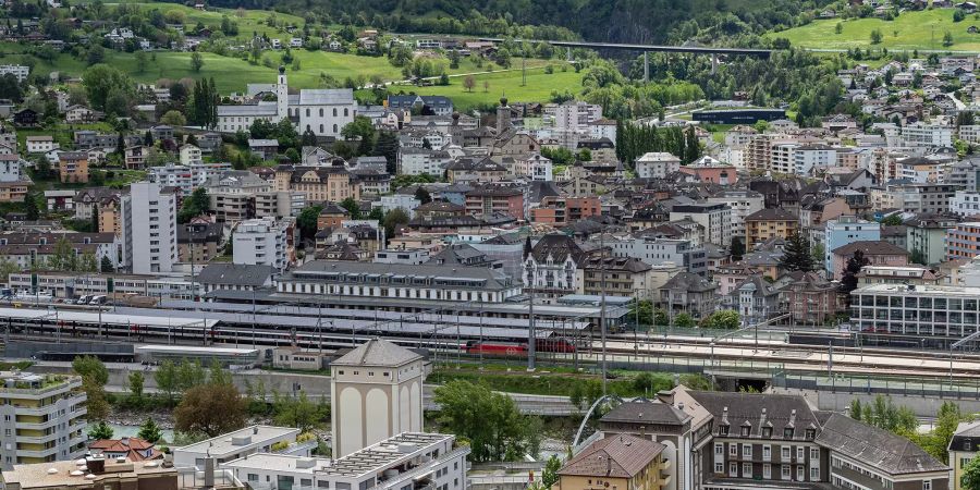 Blick auf Brig mit der A9 Simplonstrasse, der Kollegiumskirche, dem Stockalperpalast sowie der Iischi Arena und dem Bahnhof.