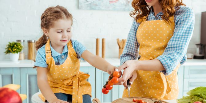 Mutter und Tochter schneiden in der Küche Tomaten