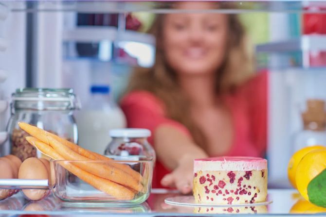 Frau schaut in Kühlschrank