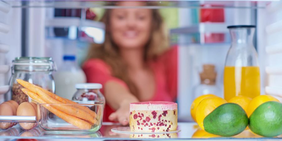 Frau schaut in Kühlschrank