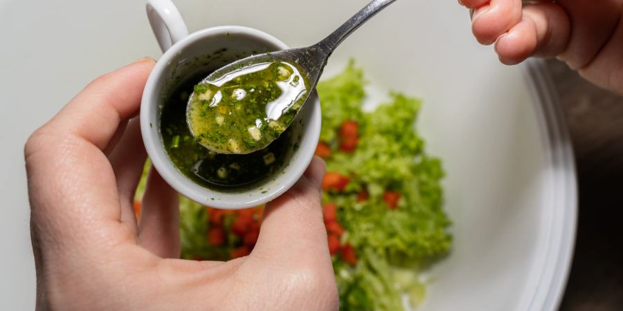 Mensch mit Salatdressing auf Löffel