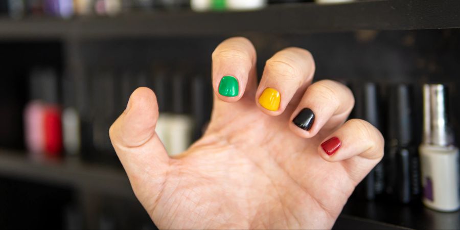 männerhand mit buntem nagellack