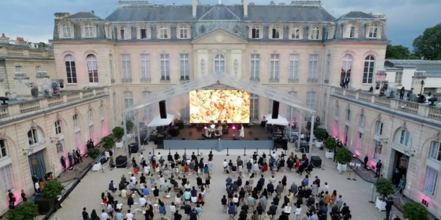 Audience members sit socially distanced in the courtyard of the Elysee Palace