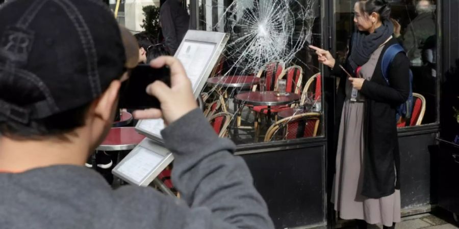 Touristen fotografieren eine kaputte Scheibe nach «Gelbwesten»-Protesten auf den Champs-Elysées