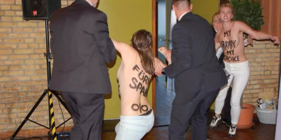 Zwei Aktivistinnen von Femen werden von Sicherhheitsbeamten aus dem Saal in Meldorf geführt. Foto: Ulrich Seehausen/Westküsten-News