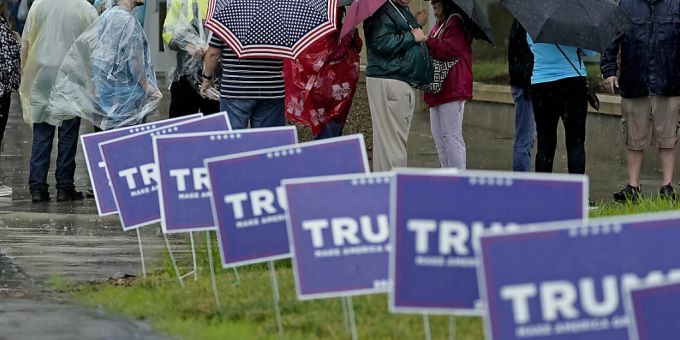 Menschen warten im Regen vor einer Kundgebung mit dem ehemaligen Präsidenten Trump. Foto: Charlie Riedel/AP/dpa Trump