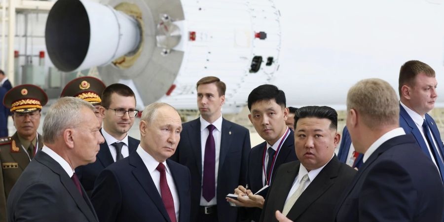 Wladimir Putin und Kim Jong-un unterhalten sich in einer Raketenmontagehalle.