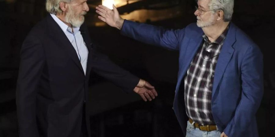 George Lucas (r) begrüsst Harrison Ford bei der Eröffnungsfeier des «Star Wars: Galaxy's Edge»-Themenparks. Foto: Chris Pizzello/Invision/AP