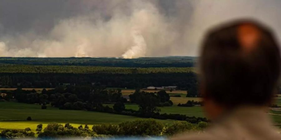 Ein Mann blickt von einem Aussichtsturm von Niedersachsen aus über die Elbe auf den Waldbrand bei Lübtheen in Mecklenburg-Vorpommern. Foto: Philipp Schulze