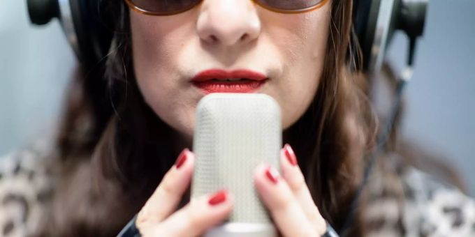 Dea Levina, Mental Domina, haucht in einem Tonstudio in ein Mikrophon. Dea Levina nimmt erotische Hörbücher im ASMR-Stil auf. erotik