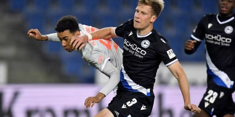 Jamal Musiala (l) von Bayern in Aktion gegen Brian Behrendt (M) von Bielefeld. Foto: Martin Meissner/AP-Pool/dpa