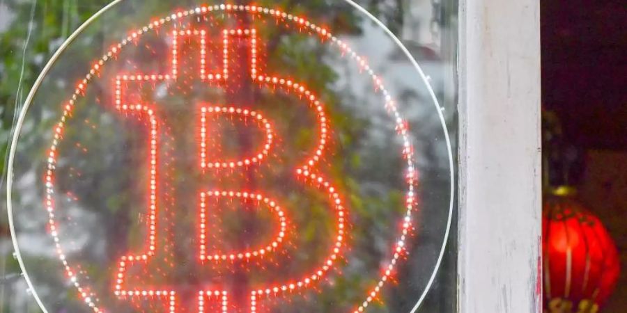 Ein Bitcoin-Logo im Schaufenster einer Kneipe im Kreuzberger Graefekiez in Berlin. Foto: Jens Kalaene/ZB/dpa