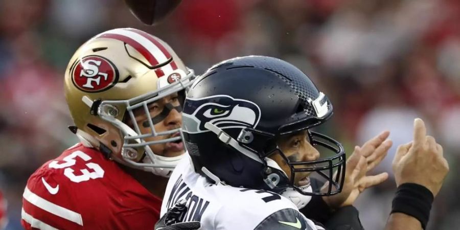 Mark Nzeocha (l) von den San Francisco 49ers in Aktion gegen Seahawks-Quarterback Russell Wilson. Foto: Tony Avelar/AP/dpa