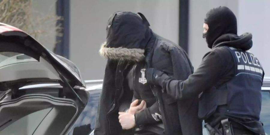 Eine Person wird von einem maskierten Polizisten in den Bundesgerichtshof in Karlsruhe gebracht. Foto: Uli Deck/dpa