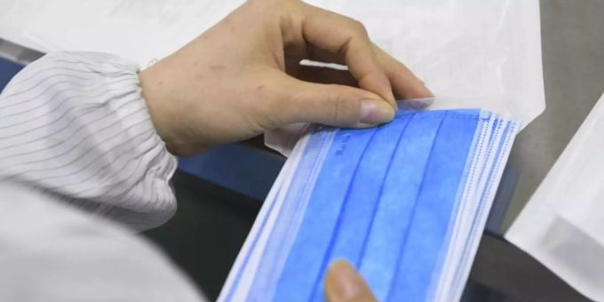 Ein Mitarbeiter eines Herstellers medizinischer Geräte verpackt Mundschutz-Masken. schutzmasken