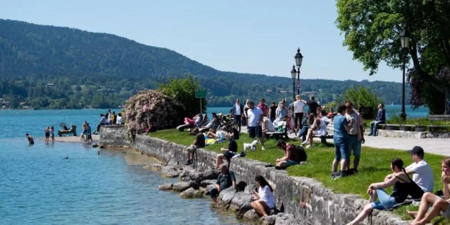 Zahlreiche Ausflügler geniessen das schöne Wetter am Ufer des Tegernsees in Bayern. Foto: Sven Hoppe/dpa