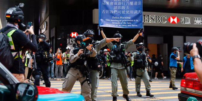 Bereitschaftspolizisten mit Waffen und einem Schild mit der Aufschrift «Warnung der Polizei: Dieses Treffen oder diese Prozession verstösst gegen das Gesetz. Zerstreut euch, oder wir können Gewalt anwenden» stehen im Central District von Hongkong regierungskritischen Demonstranten gegenüber. Proteste in Hongkong