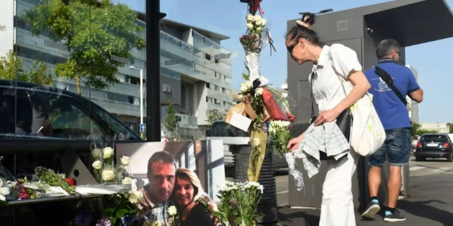 Eine Frau in Bayonne legt Blumen am Bild von Philippe und Véronique Monguillot ab