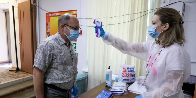 Eine Mitarbeiterin der Wahlkommission trägt einen Schutzanzug und überprüft die Körpertemperatur eines Wählers in einem Wahllokal in Moskau. Die russische Hauptstadt hat nun die Maskenpflicht trotz hoher Corona-Zahlen gelockert. Abstimmung über Verfassungsänderung in Russland