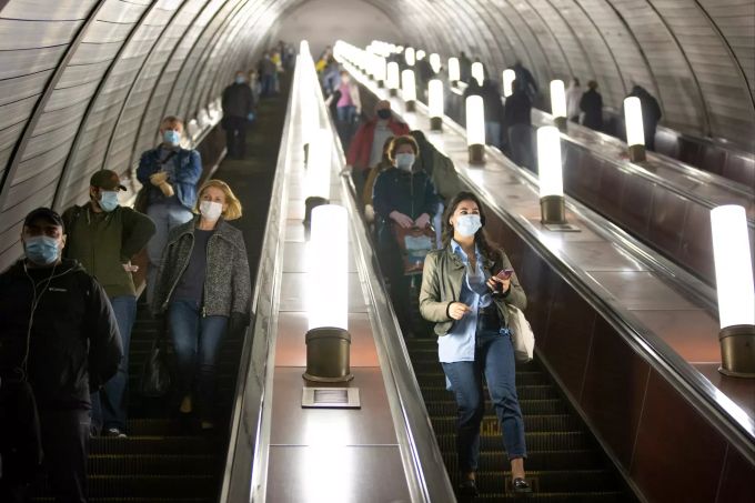 Menschen in Moskau, die zum Schutz vor Coronaviren Gesichtsmasken und Handschuhe tragen, halten sich an die Richtlinien zur sozialen Distanzierung, während sie auf der Rolltreppe zur U-Bahn hinuntergehen. Ab Dienstag ist das Tragen von Gesichtsmasken und Latexhandschuhen für Personen, die die öffentlichen Verkehrsmittel in Moskau benutzen, Pflicht. Coronavirus - Russland