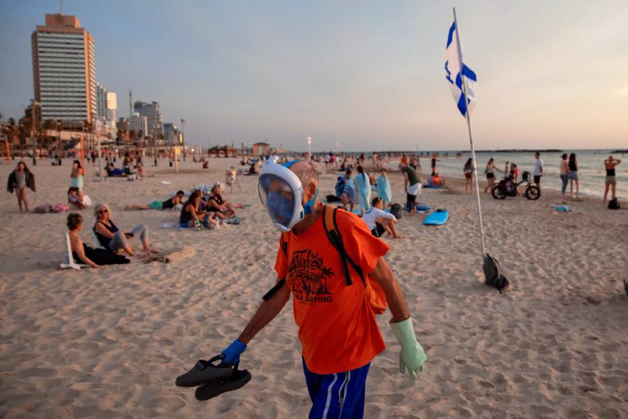 Ein älterer Mann trägt am Samstag, 16. Mai, am Strand von Tel Aviv Handschuhe und eine Tauchermaske, die er als schützende Gesichtsmaske an der Strandpromenade verwendet.