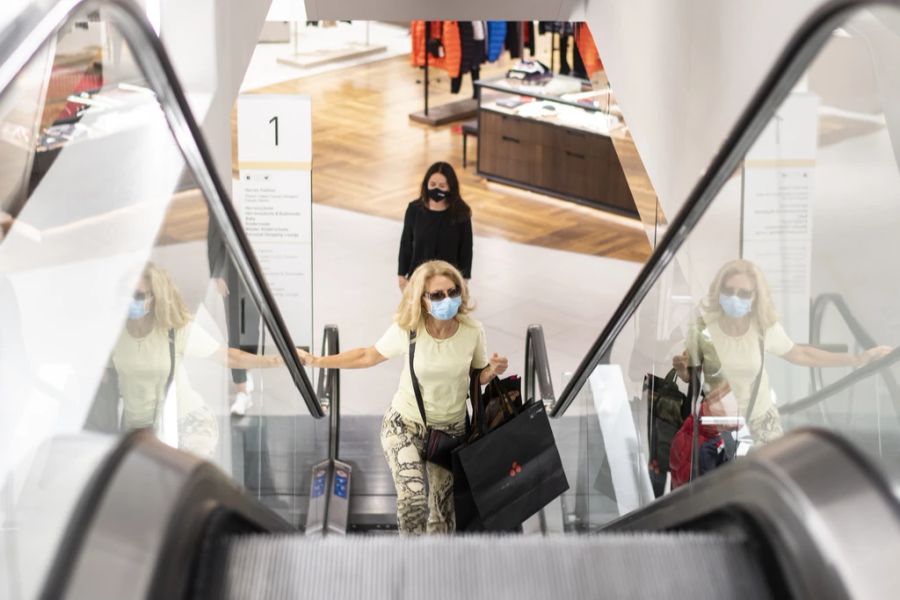 Menschen mit Atemschutzmasken fahren auf der Rolltreppe, aufgenommen im Warenhaus Jelmoli in Zürich.