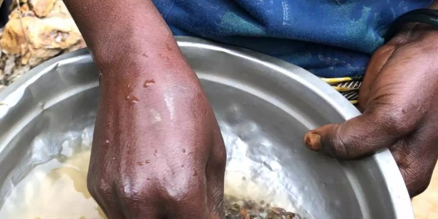 Eine Frau wäscht in der Mine Zola Zola bei Nzibira in der ostkongolesischen Provinz Süd-Kivu auf der Suche nach wertvollen Mineralien Gestein aus. Über weltweite Lieferketten gelangen sie in Handys und Autos. Foto: Jürgen Bätz/dpa