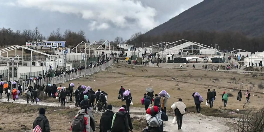 Migranten gehen am 30. Dezember 2020 mit ihren Habseligkeiten zurück zum Lager Lipa. Foto: Kemal Softic/AP/dpa