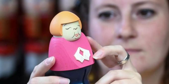 Sina Klement komplettiert in der Schauwerkstatt der Seiffener Volkskunst in Seiffen eine Merkel-Figur. Foto: Hendrik Schmidt/dpa-Zentralbild/ZB Sina Klement komplettiert in der Schauwerkstatt der Seiffener Volkskunst in Seiffen eine Merkel-Figur. Foto: Hendrik Schmidt/dpa-Zentralbild/ZB