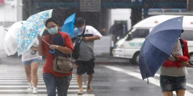 Menschen mit Regenschirmen kämpfen in Keelung gegen das Unwetter. Foto: Daniel Ceng Shou-Yi/ZUMA/dpa
