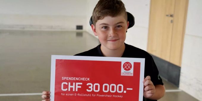 Dank grosszügigen Spenden erhält Noah endlich seinen E-Rollstuhl fürs Powerchair Hockey. Junge mit Spendencheck