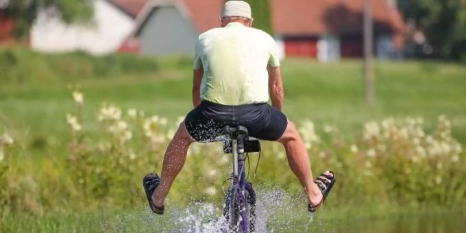 Ein Radfahrer fährt in Sandalen auf dem vom Regen überfluteten Donau-Radwanderweg durch das Hochwasser. Foto: Thomas Warnack/dpa Ein Radfahrer fährt in Sandalen auf dem vom Regen überfluteten Donau-Radwanderweg durch das Hochwasser. Foto: Thomas Warnack/dpa