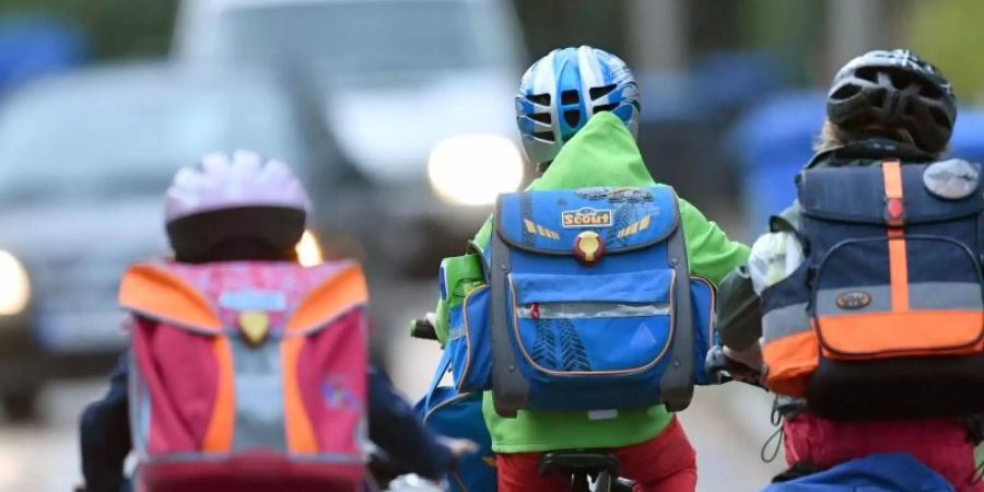 Kinder sind auf einer Strasse mit dem Fahrrad unterwegs zur Schule. Symbolbild. Foto: Ralf Hirschberger/dpa-Zentralbild/dpa