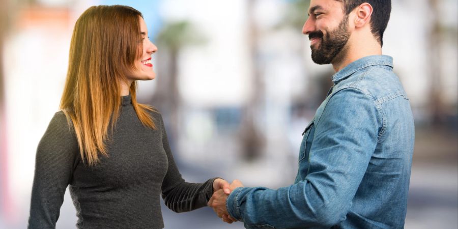 mann und frau schütteln sich die hände, urbaner hintergrund