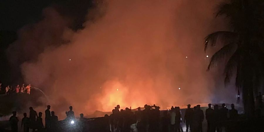 Menschen arbeiten daran, ein Feuer in einem behelfsmässigen Markt in der Nähe eines Rohingya-Flüchtlingslagers zu löschen. Das Feuer brach am frühen heutigen Freitag aus. Foto: Shafiqur Rahman/AP/dpa